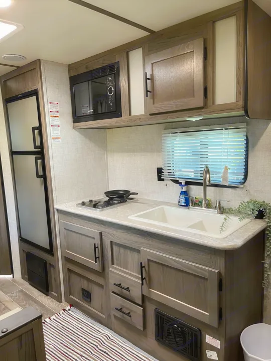 Well-equipped RV rental kitchen featuring a fridge, microwave, gas stove, and double sink.. Travel Lite Superlite 2022