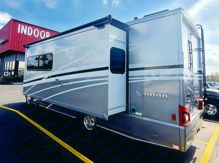 A modern silver Navion RV rental with its side slide-out extended, parked at an outdoor dealership.. Winnebago Navion 2020