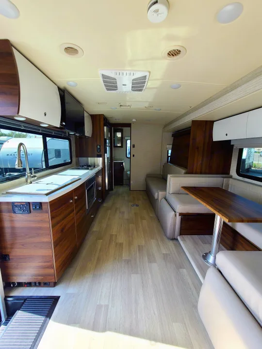 Spacious, modern RV rental interior featuring a bright kitchen, dining table, and plush seating.. Winnebago Navion 2020