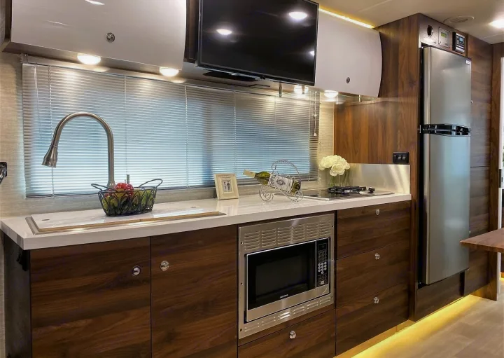 Step into this luxurious RV rental. A well-equipped kitchen features a modern sink, microwave, fridge, and ample counter space.. Winnebago Navion 2020
