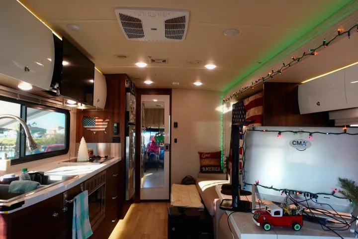 Bright RV rental interior: Full kitchen, cozy seating, and festive lights with patriotic American flag decor.. Winnebago Navion 2020