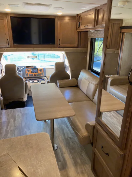 Experience comfort in this RV rental's inviting interior, showcasing a functional cockpit, dinette, and overhead TV.. Gulf Stream B Touring Cruiser 2019