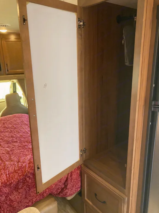 RV rental wardrobe with open door, revealing storage, a hanging bar, and a bed in the background of this RV interior.. Gulf Stream B Touring Cruiser 2019