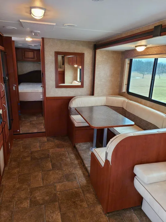 Spacious RV rental interior: comfortable dining area, open bedroom view, and tile floor.. Winnebago Minnie Winnie 2014
