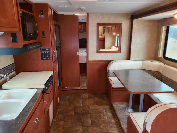 Spacious RV rental interior featuring a kitchen, U-shaped dinette, and a private bedroom.. Winnebago Minnie Winnie 2014