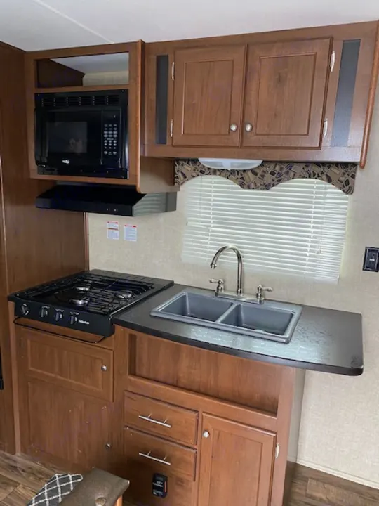 RV rental kitchen: compact sink, stove, microwave, & cabinets. Ideal for mobile cooking & dining.. prowler lynx 22LX 2015