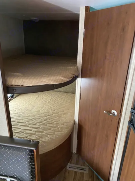Inside an RV rental: an open storage compartment reveals cushions for a versatile sleeping area.. prowler lynx 22LX 2015