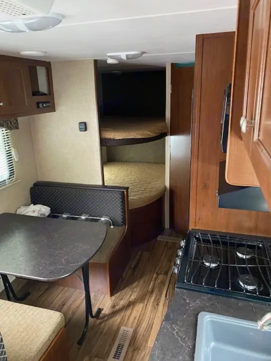 Compact RV rental interior with kitchen, dinette, and bunk beds. Perfect for family adventures!. prowler lynx 22LX 2015