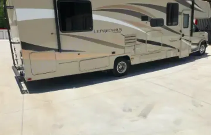 A beige & brown Leprechaun Class C RV rental, perfect for travel & outdoor adventures, parked on concrete.. Forest River Coachmen Leprechaun 2018