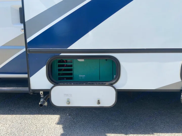 Side of an RV rental with an open compartment revealing an Onan QG 4000 generator and exhaust pipe, providing power on the go.. Winnebago Outlook 2020