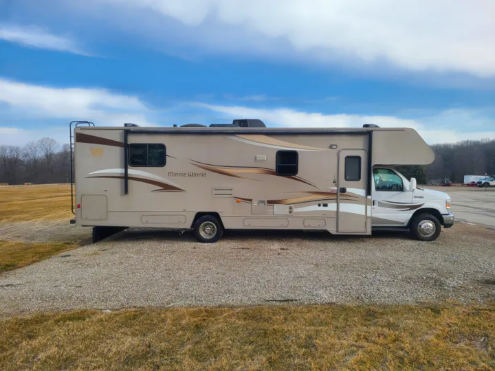 Beige Class C Winnebago Minnie Winnie RV on gravel under blue sky, ready for your next rv rental adventure.. Winnebago Minnie Winnie 2014
