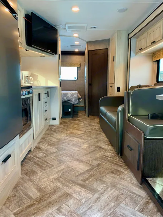 Spacious RV rental interior featuring a modern kitchen, comfortable dinette, and bedroom area with herringbone flooring.. Forest River Forester 2551DSLE 2021