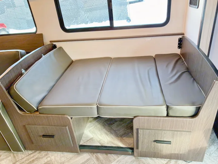 RV rental interior: Versatile dinette with dark cushions converts to a bed. Wood-look finishes and under-seat storage are visible.. Forest River Forester 2551DSLE 2021