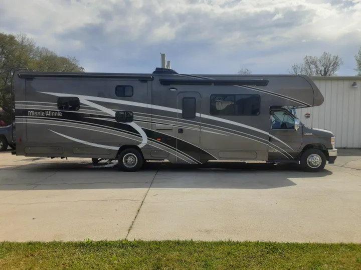 Gray Winnebago Minnie Winnie RV rental, a Class C motorhome, parked on a concrete lot ready for adventure.. CLASS C 2022