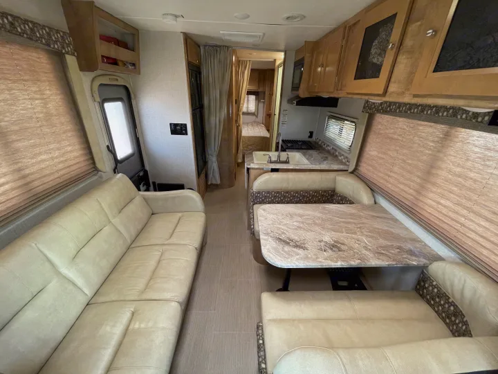 Spacious RV rental interior featuring a lounge sofa, dinette, kitchenette, and rear bedroom for travel comfort.. Coachmen Leprechaun 2019