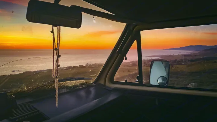 Gorgeous golden sunset over the ocean from an RV rental. View from inside a camper van on a coastal road trip.. Volkswagen Vanagon 1984