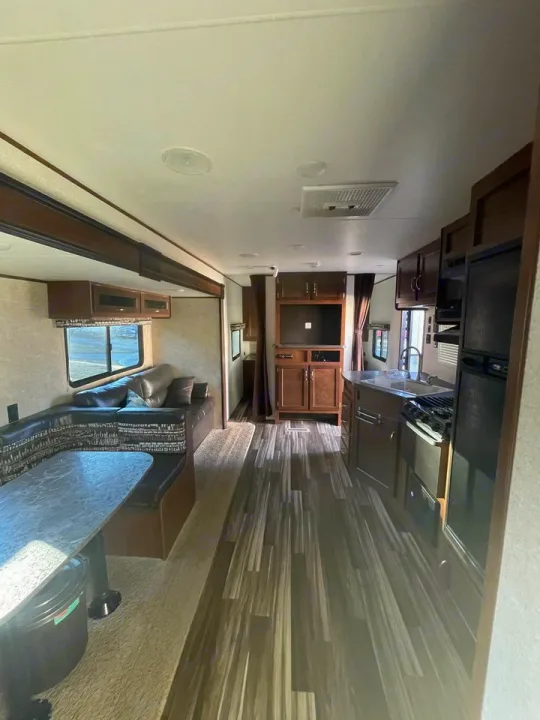 Spacious RV rental interior showcases a cozy dinette, modern kitchen, and comfortable living area with wood-look flooring.. Jayco 32 BHS 2017