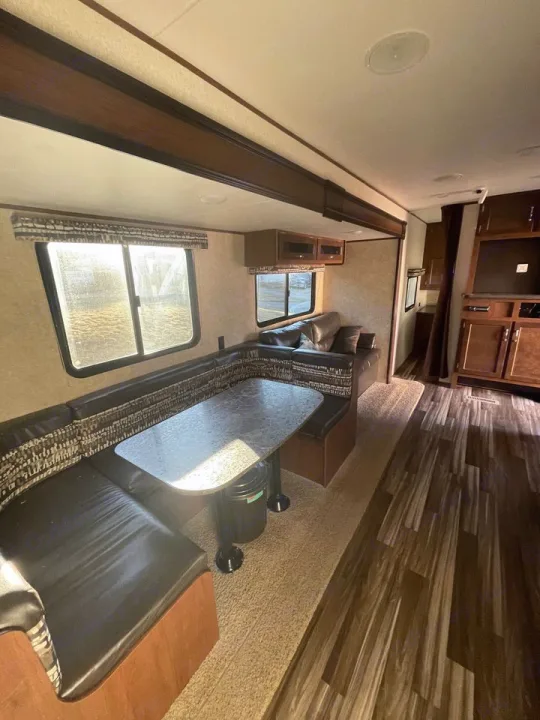 Bright RV rental interior featuring a spacious dining booth, cozy lounge area, and wood-look flooring.. Jayco 32 BHS 2017