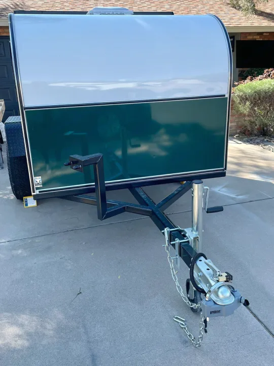 Custom-built RV rental trailer: a compact, white and dark green unit with a robust hitch and front jack stand.. Other Other 2022