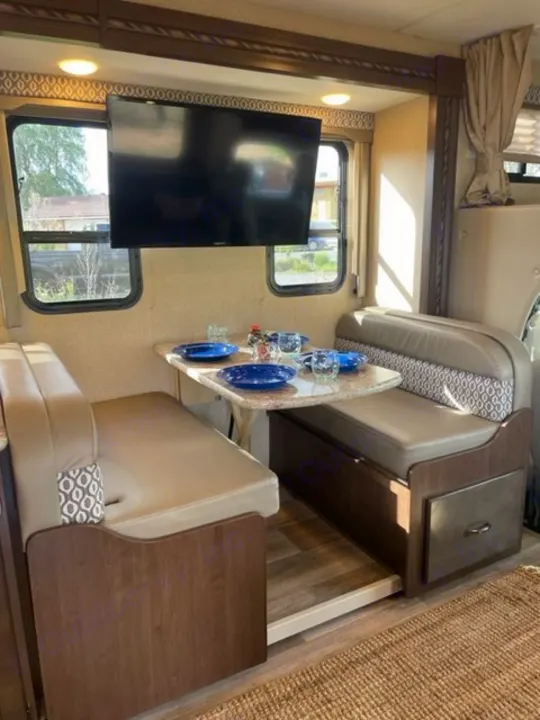 Spacious RV rental dinette, set with dishes, features a large TV for comfortable journeys.. Thor Freedom Elite 2018