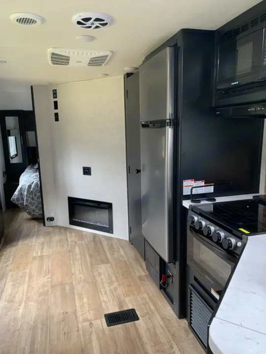 Explore this modern RV rental's inviting interior: sleek kitchen with stainless fridge, stove, oven, fireplace, & bedroom.. Forest River Cherokee 2022