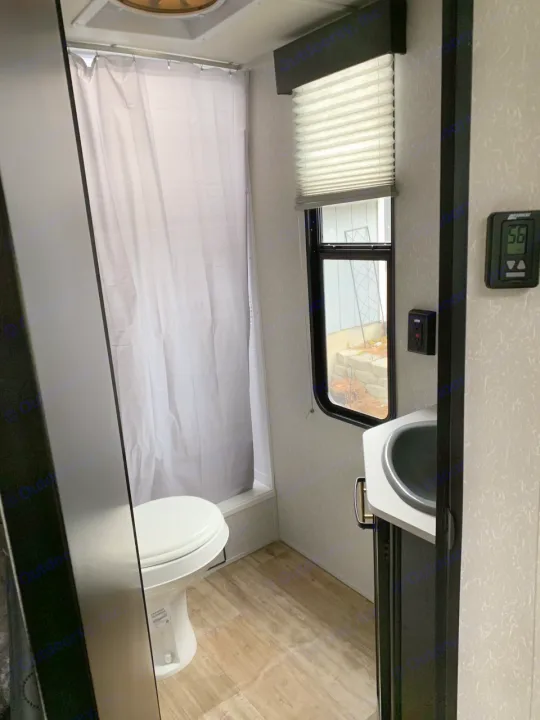 Experience comfort in this rv rental's compact bathroom, featuring a toilet, shower, sink, and window.. Forest River Cherokee 2022