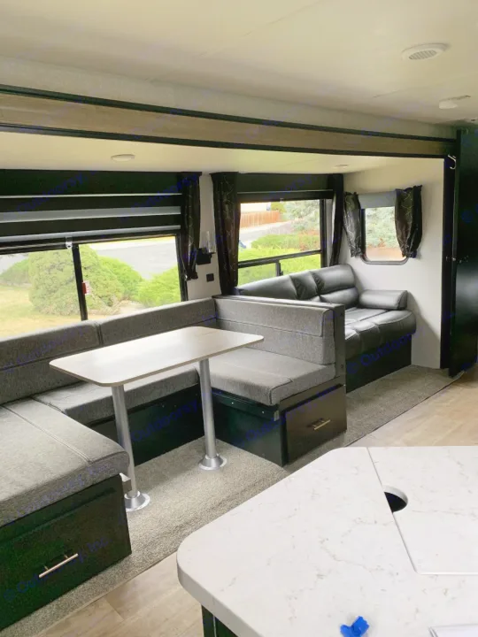 Spacious RV rental interior featuring a modern dinette, comfortable sofa, and kitchen counter for your travel comfort.. Forest River Cherokee 2022