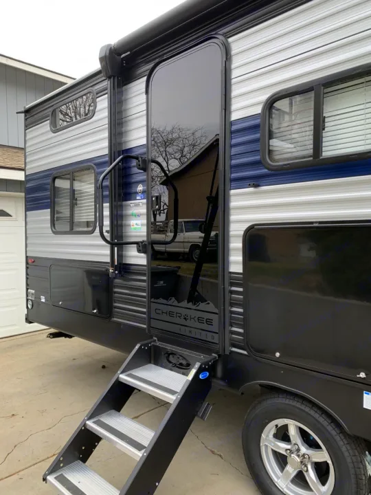 Explore this RV rental: A blue and grey Cherokee Limited travel trailer with steps leading to its reflective black entry door.. Forest River Cherokee 2022