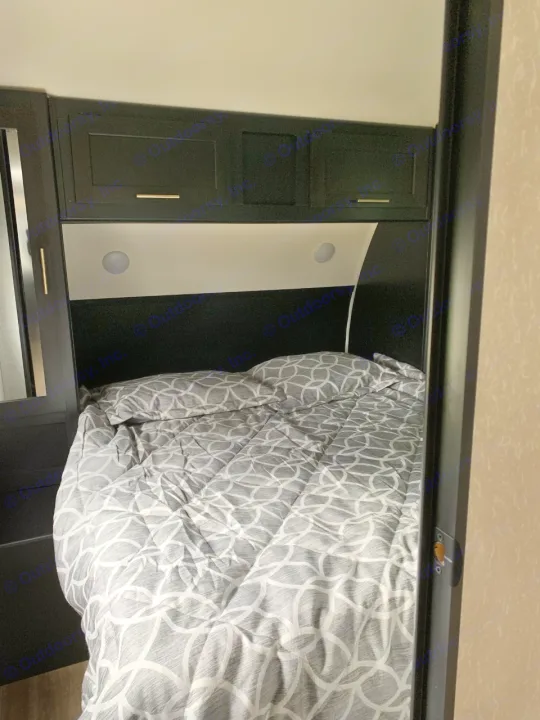 RV rental bedroom: Gray patterned bedding, dark overhead cabinets, and recessed lights provide a cozy sleeping space.. Forest River Cherokee 2022