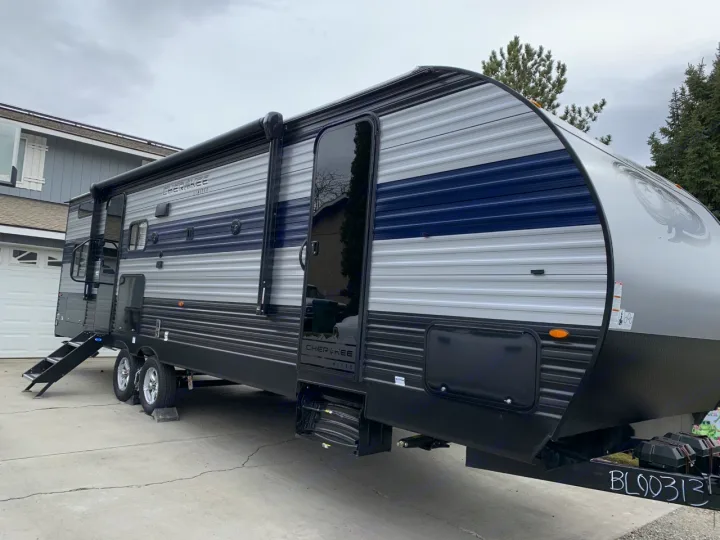 This modern travel trailer RV rental, parked on a paved driveway with steps extended, is ready for your adventure.. Forest River Cherokee 2022