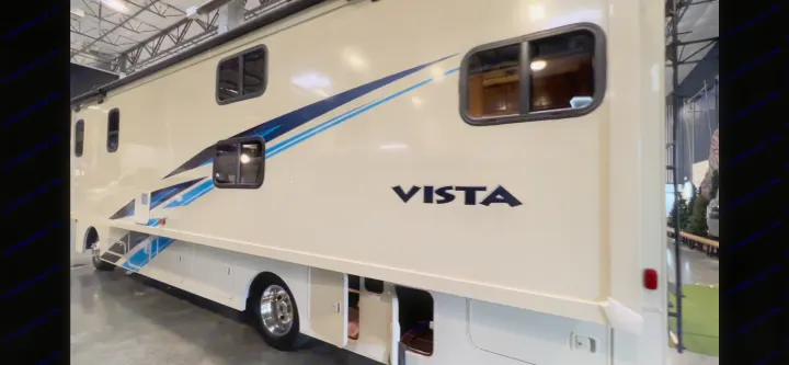 Large beige RV with blue stripes & 'VISTA' lettering on its side, showing open storage. Perfect for an rv rental vacation.. Winnebago Vista 2019