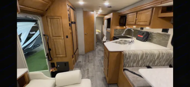 Explore this **rv rental** interior: a modern kitchen, inviting dining area, and hallway leading to bunks. Great for travel adventures.. Winnebago Vista 2019