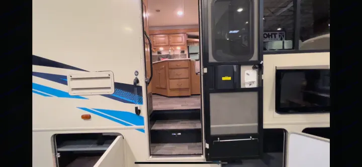 This RV rental showcases its open entry door, revealing a kitchen, interior steps, and exterior storage.. Winnebago Vista 2019