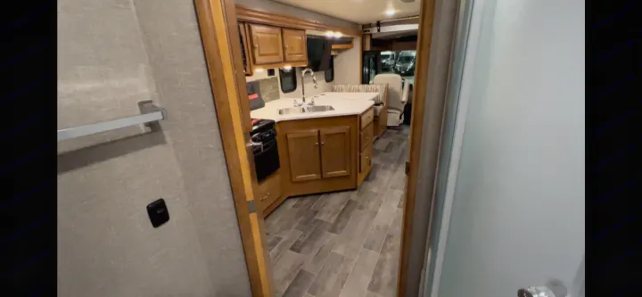 RV rental interior: View into a modern kitchen, dining area, and cockpit from a bathroom doorway.. Winnebago Vista 2019