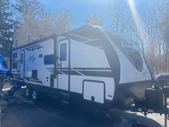 Explore with this Imagine RV rental. A modern white & black travel trailer, parked outside on a sunny day.. Grand Design 2800BH 2021