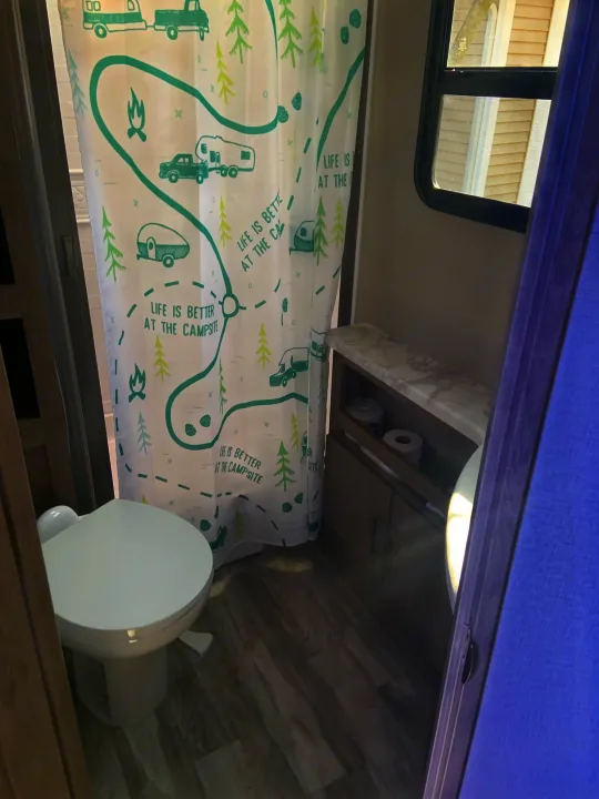 RV rental bathroom: features a toilet, shower with a 'Life is Better at the Campsite' curtain, and built-in storage.. Grand Design 2800BH 2021
