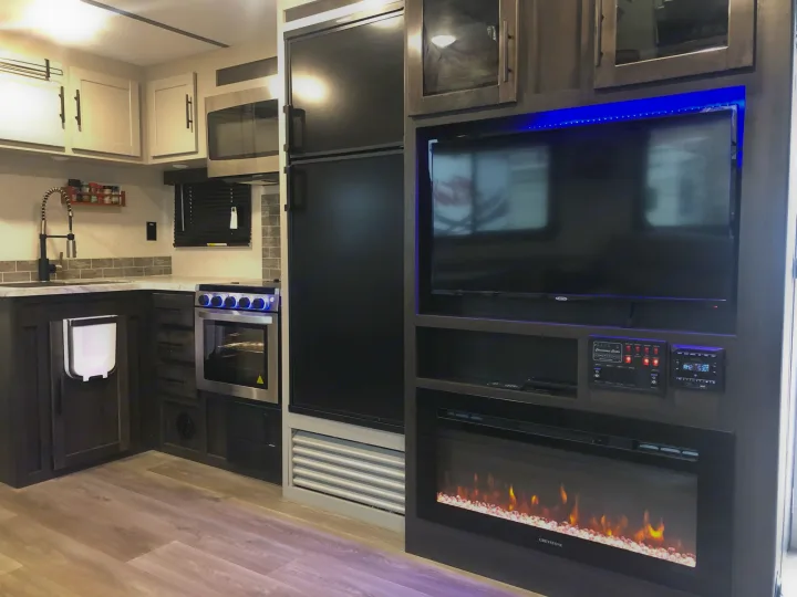 Modern RV rental interior featuring a full kitchen, living area with TV, and cozy electric fireplace for comfort.. Crossroads Cruiser Aire 2021