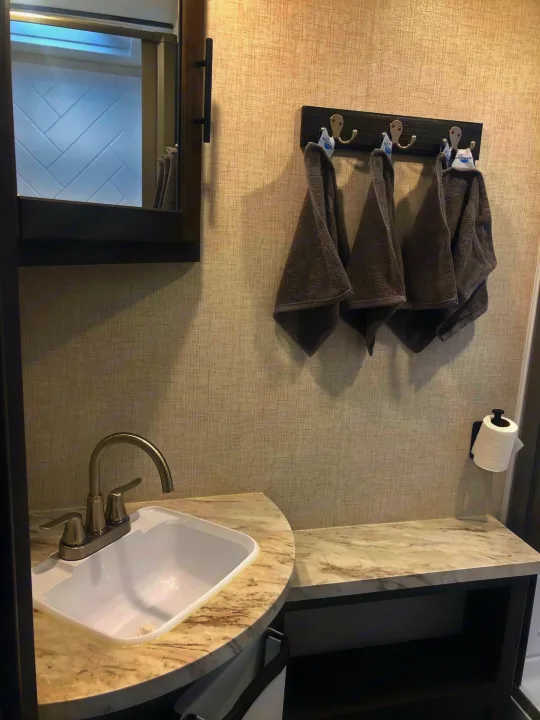 Compact rv rental bathroom: sink, vanity, mirror, wall hooks with towels, and toilet paper holder.. Crossroads Cruiser Aire 2021