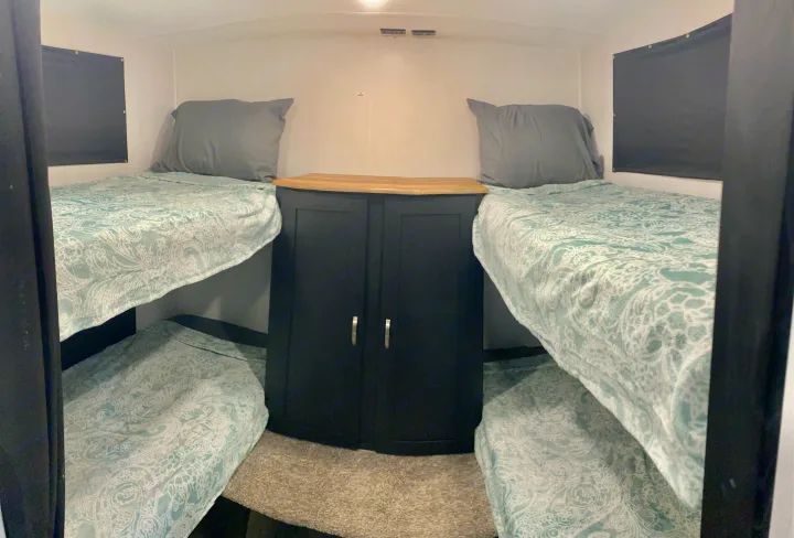 RV rental sleeping space featuring four bunk beds with light blue patterned bedding and a central wood-top cabinet.. Coachmen Freedom express select 2022