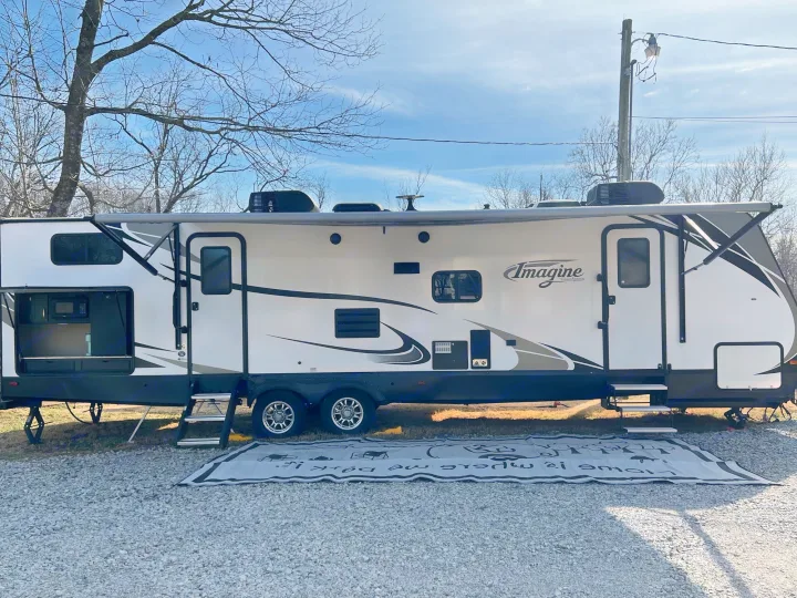 Spacious Imagine travel trailer, an ideal rv rental, parked on a gravel site. Awning is out, inviting outdoor enjoyment.. Grand Design Imagine 2018