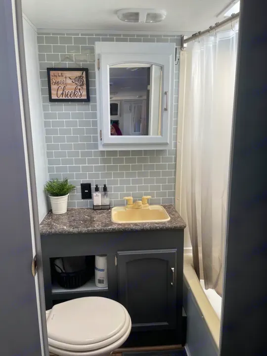 Step inside this modern RV rental bathroom featuring stylish gray subway tiles, a functional vanity, and a cozy shower.. Keystone RV Springdale 2015