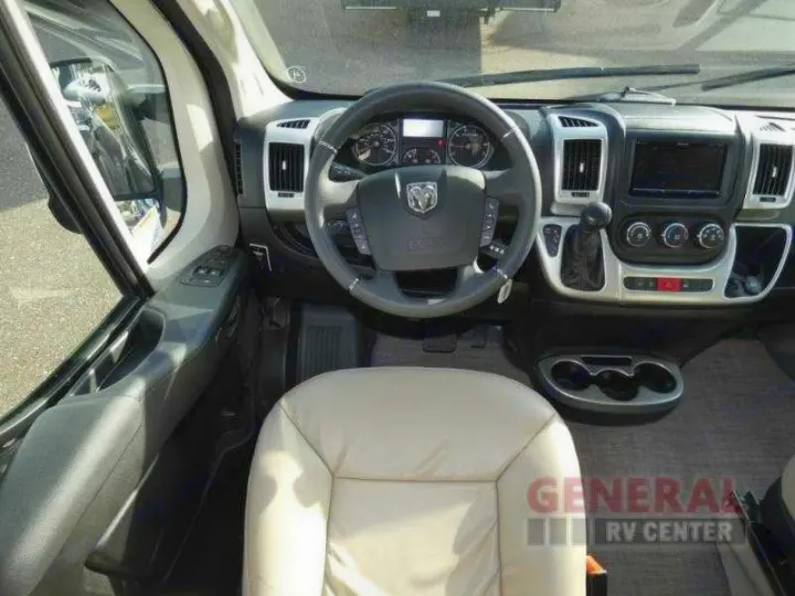 Inside an RV rental, showing the driver's cockpit, steering wheel with a Ram logo, and dashboard from the passenger side.. Thor Scope 2022