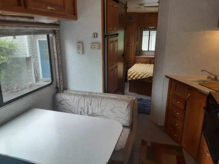 Cozy RV rental interior featuring a comfortable dinette, functional kitchen, and private bedroom area.. Jayco Eagle 1996