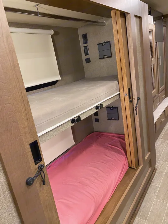 An RV rental's built-in bunk beds, complete with mattresses, window shades, and power outlets.. Thor 37.1 2022
