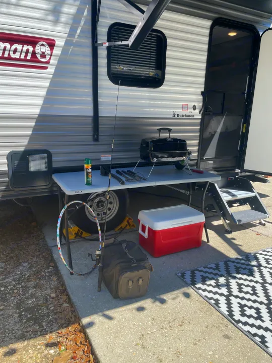 An RV rental, complete with a portable grill, fishing rod, cooler, and outdoor table for a perfect camping setup.. Dutchmen Coleman Lantern 2022