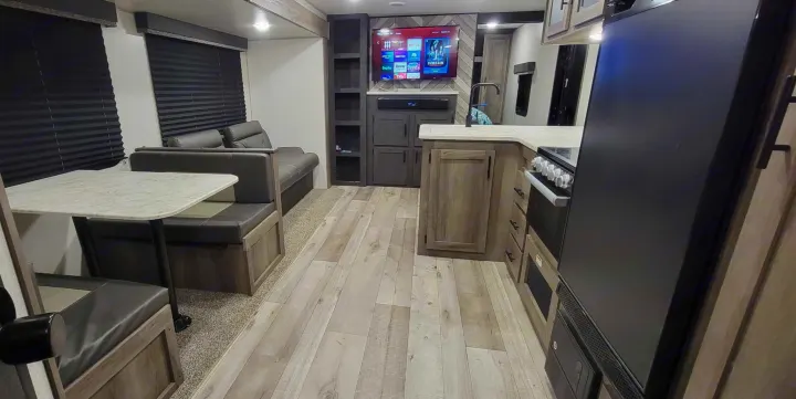 Modern RV rental: a spacious interior with kitchen, dinette, and living area featuring an entertainment center.. Sportsmen SE 2021