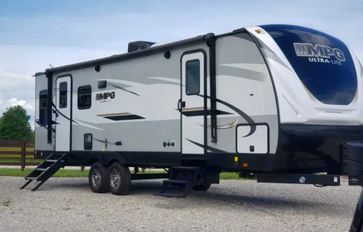 Modern grey & white MPG Ultra-Lite travel trailer. This RV rental is parked on gravel, ready for your outdoor adventures.. Cruiser RV MPG Ultra Lite 2020