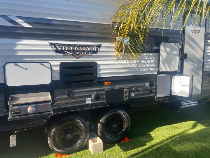 Wildwood X-Lite RV rental with outdoor kitchen (griddle & fridge) set up on grass, perfect for travel and camping.. Forest River 263BHXL 2022