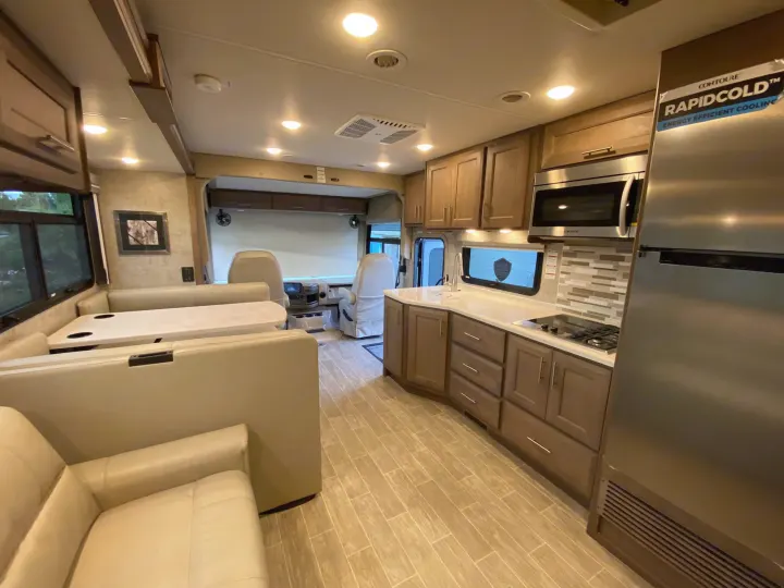Spacious and modern RV rental interior featuring a full kitchen, dining booth, and cozy living space.. Thor 37.1 2022