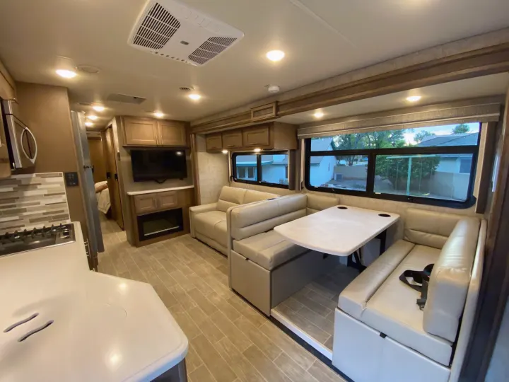 Spacious RV rental interior featuring a modern kitchen, comfortable lounge, and a dinette area with large windows.. Thor 37.1 2022